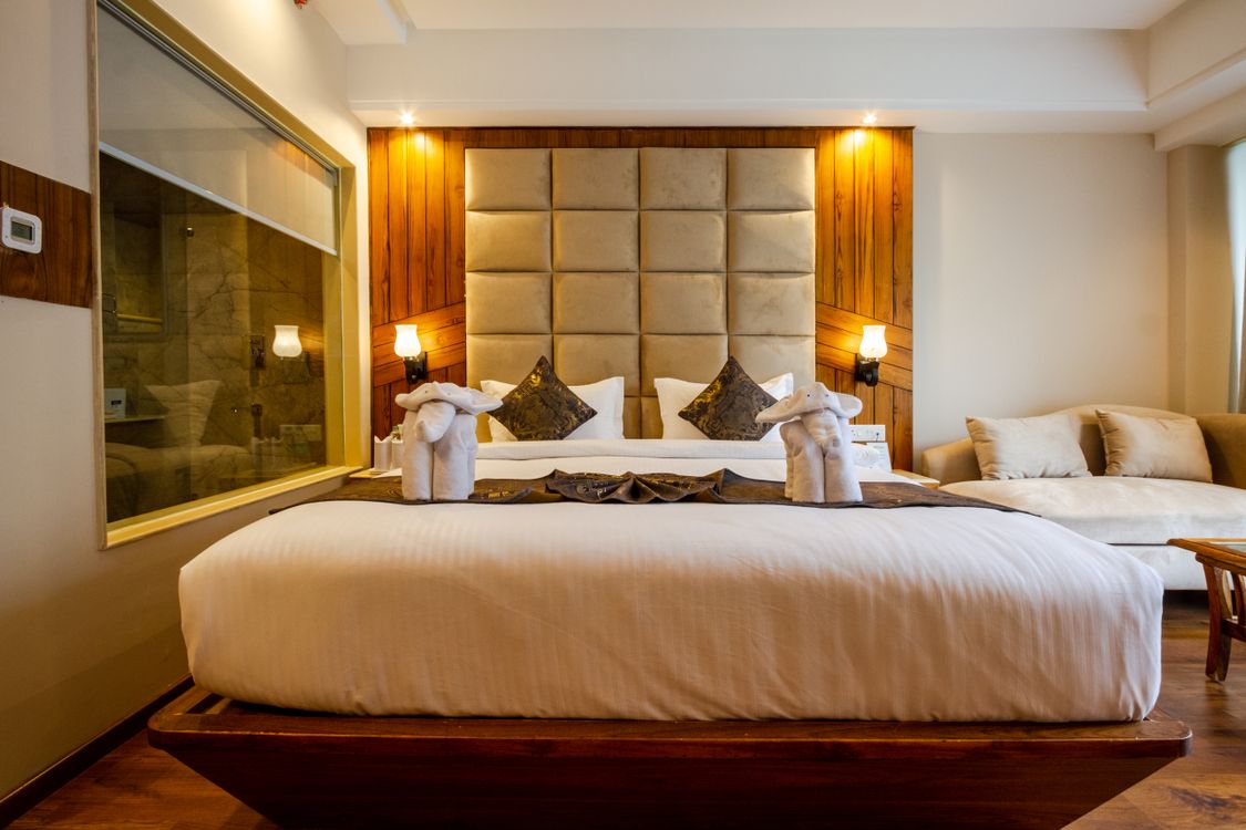 Illustrative hotel guest room with a large bed, warm lighting and decorative towels; stock photo by SVH Manali