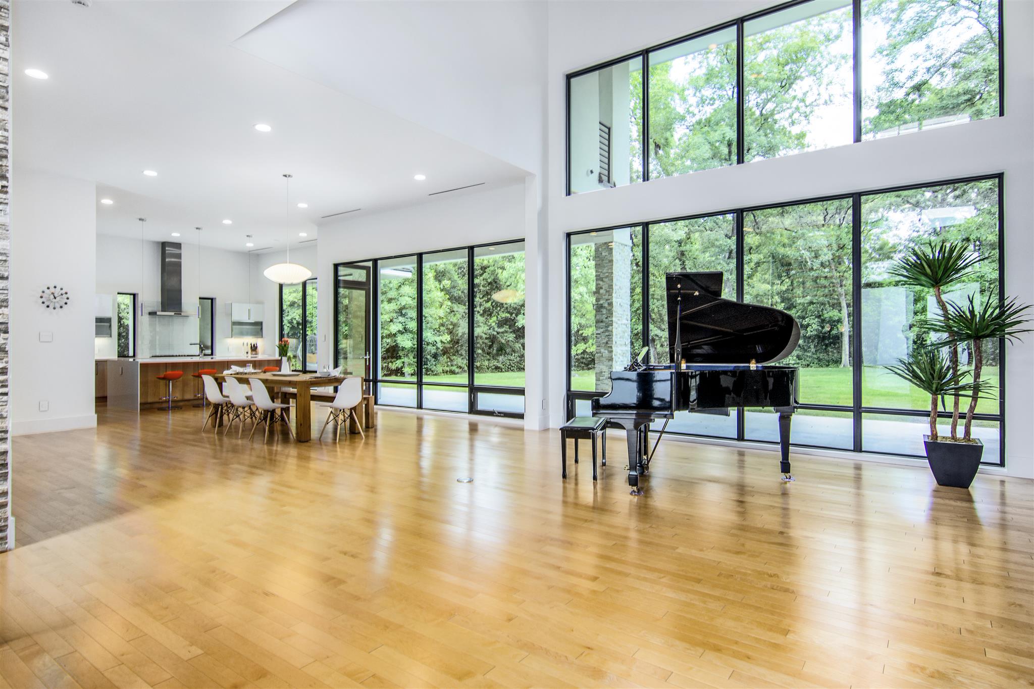 Open living and dining area with large windows facing green foliage
