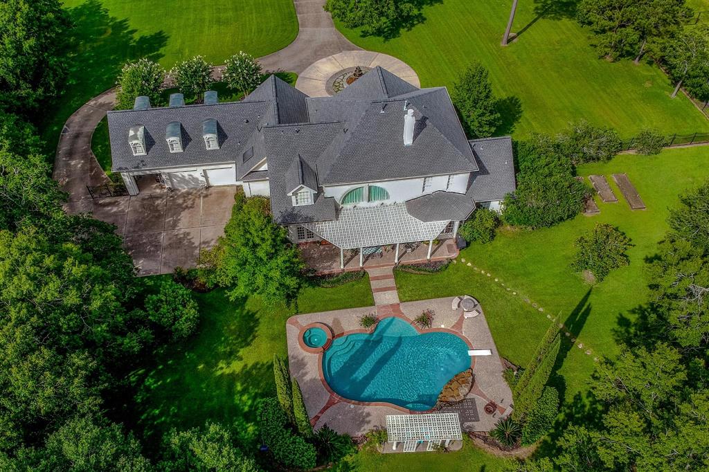 Drone overhead real estate photo showing a home, pool, and surrounding green lawn